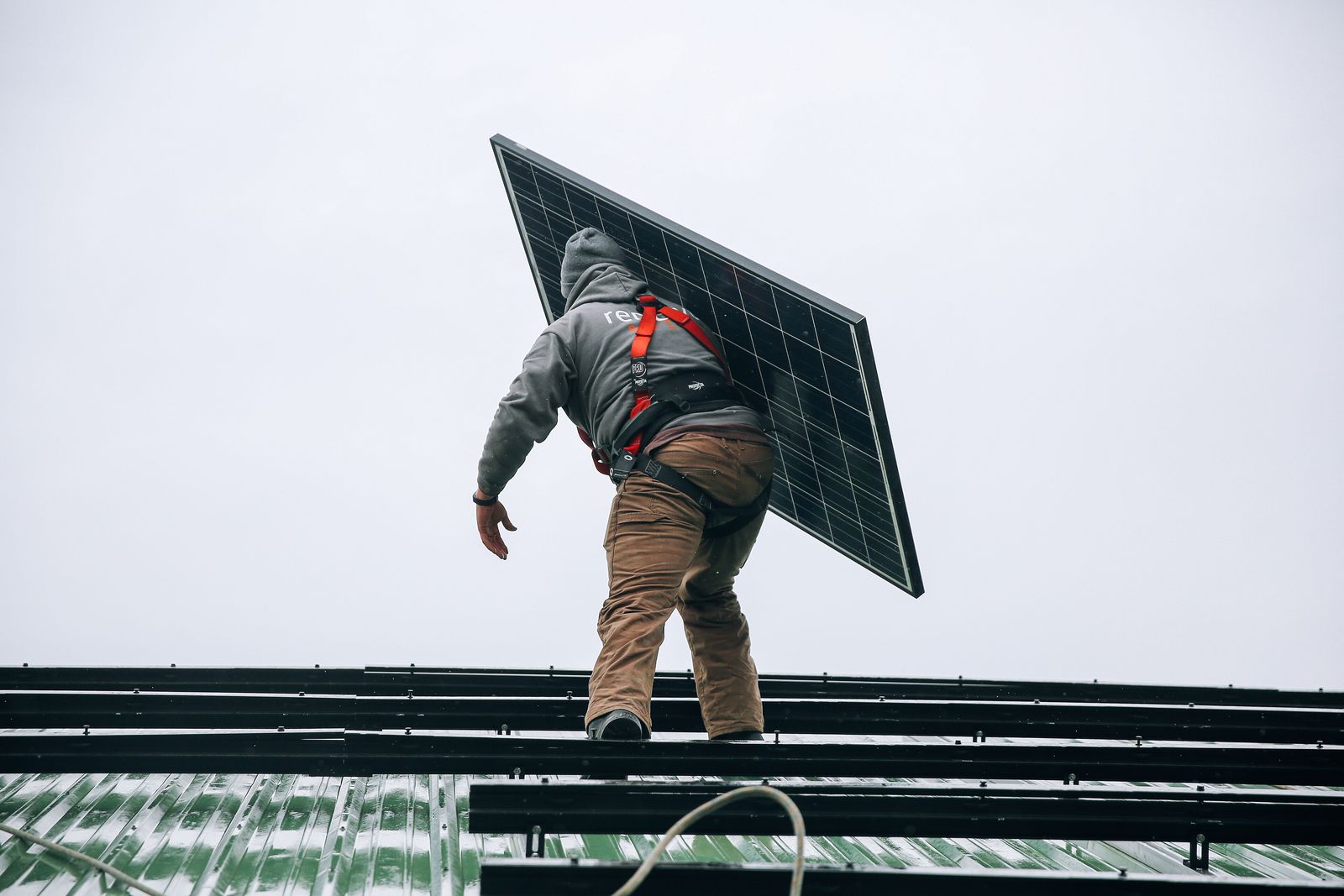 Installer carrying a solar panel onto a roof